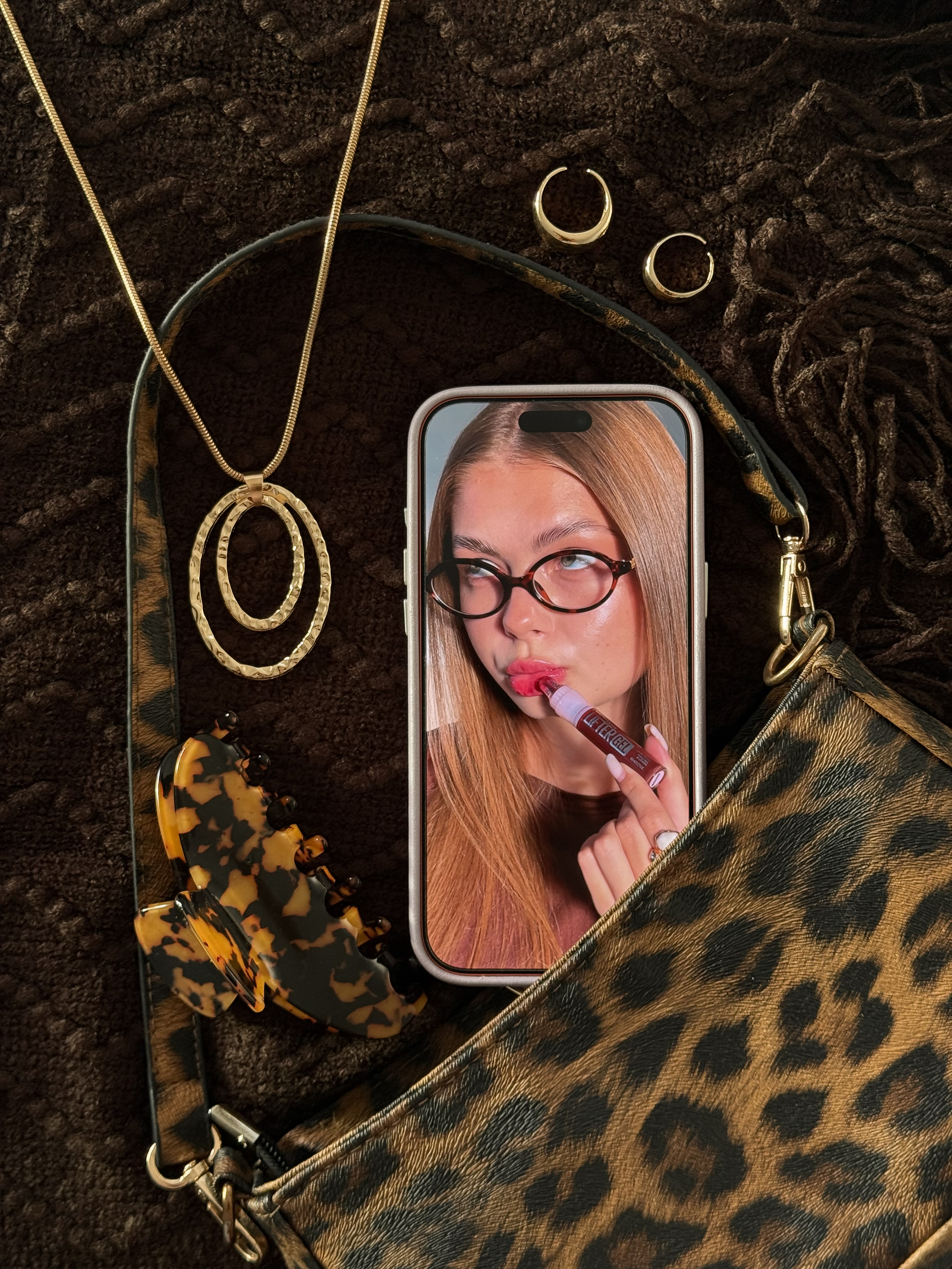 Beauty flat lay with lip gloss portrait on a phone and leopard print accessories